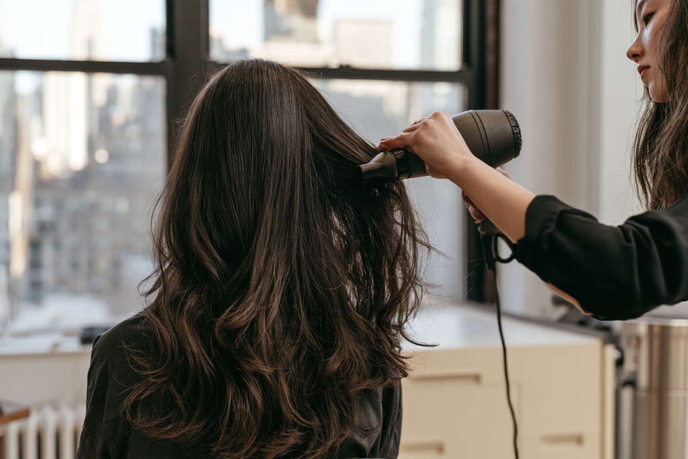 Client’s finished layered hair with a stylist blow-drying on the right
